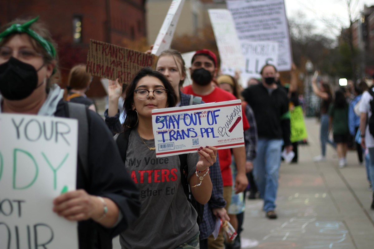 A protestor holds a sign that reads "Stay out of trans people's business."